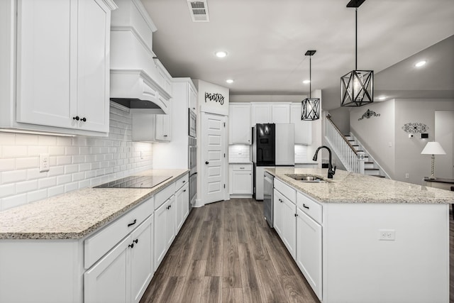 kitchen with a kitchen island with sink, sink, stainless steel appliances, and white cabinets