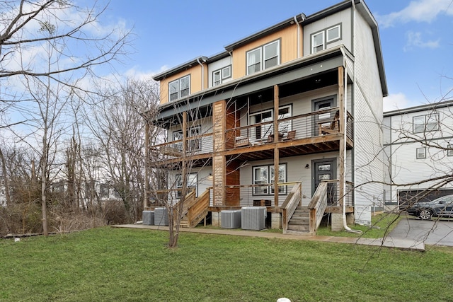 rear view of property with central AC unit and a lawn