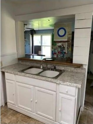 kitchen featuring light stone countertops, sink, and white cabinets