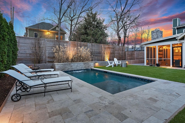 pool at dusk with a lawn, a patio, central AC unit, a sunroom, and pool water feature