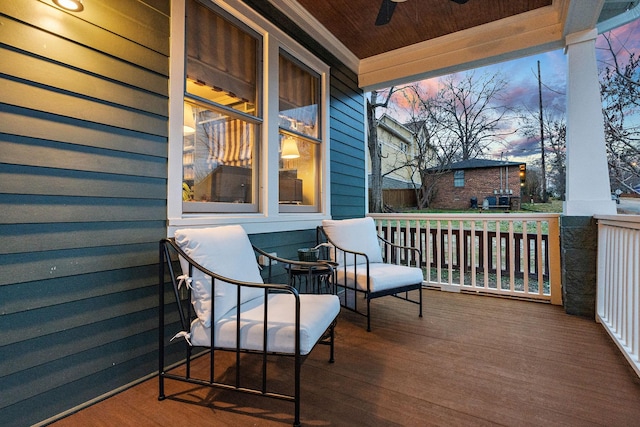 deck at dusk featuring ceiling fan and covered porch