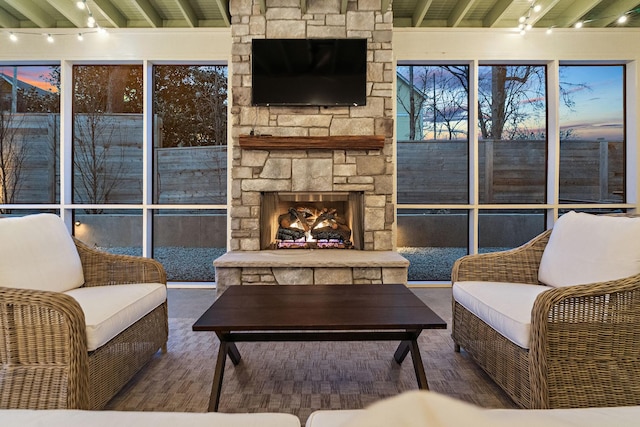 living room with an outdoor stone fireplace and beamed ceiling