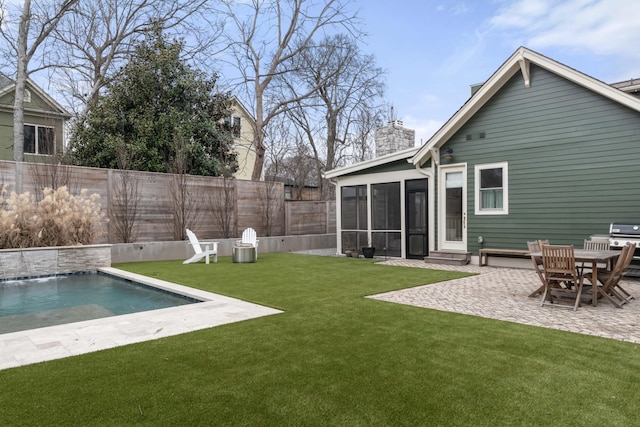 rear view of property with a sunroom, a lawn, pool water feature, and a patio area