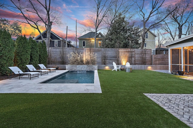 pool at dusk with pool water feature, a yard, a sunroom, and a patio area