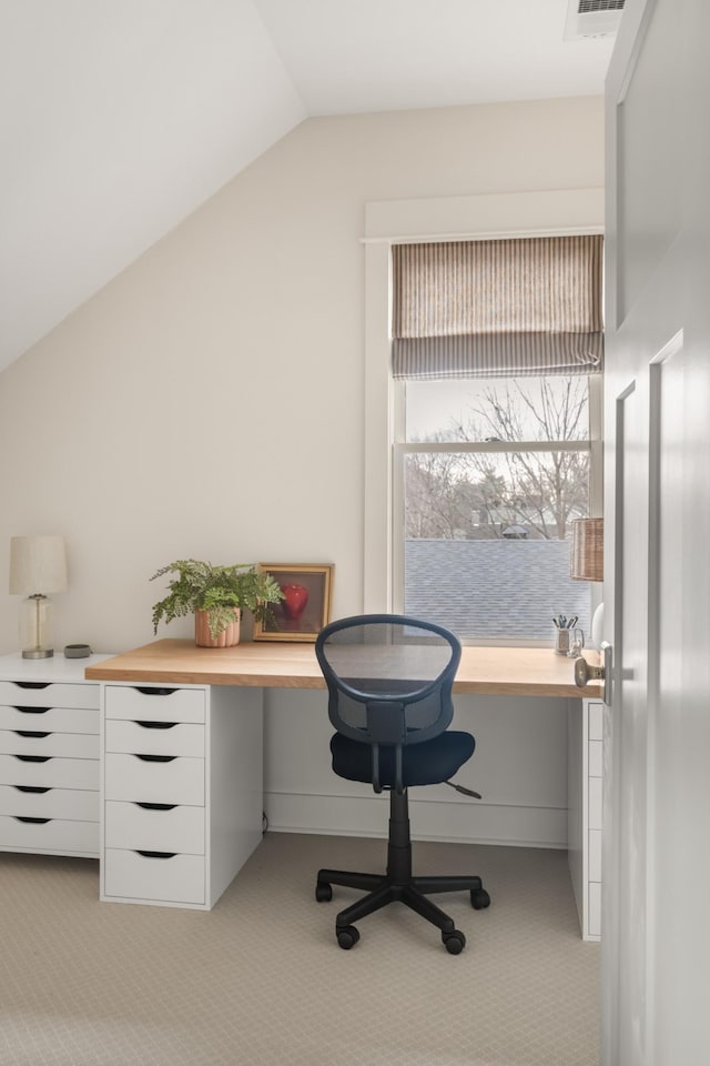 carpeted home office with lofted ceiling and built in desk