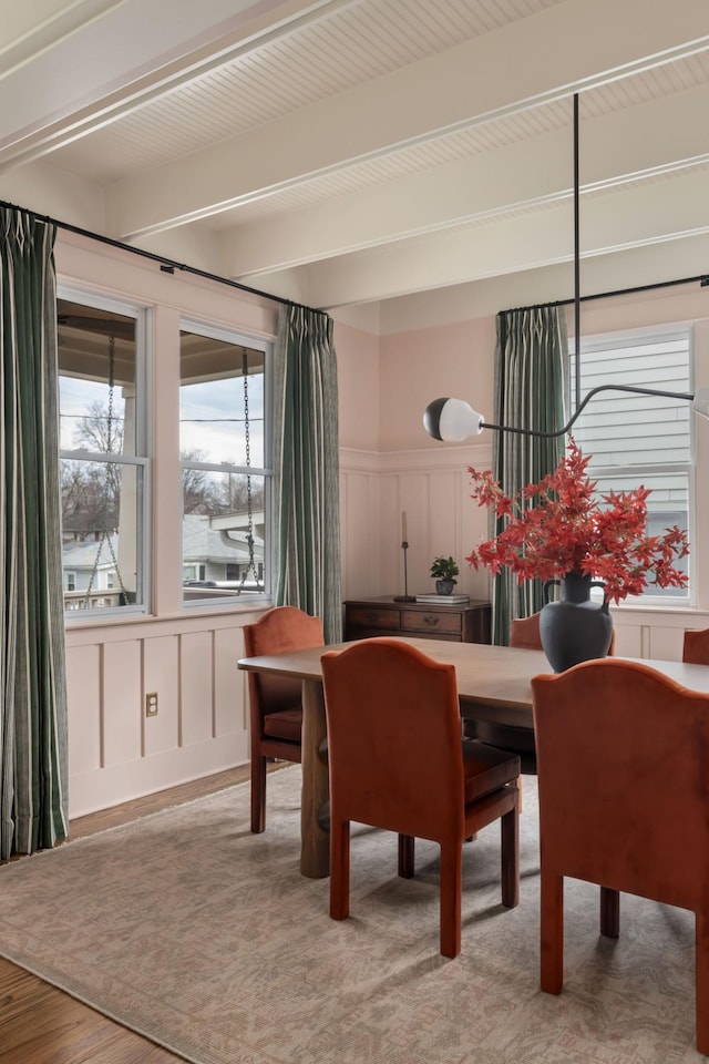 dining area with beam ceiling and light hardwood / wood-style flooring