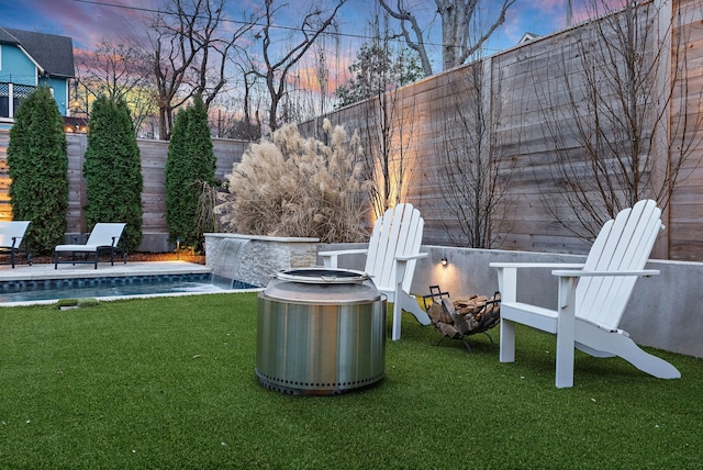 yard at dusk with a pool and pool water feature