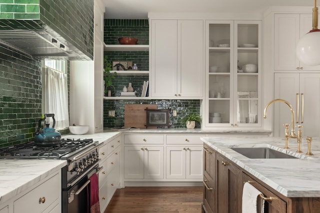 kitchen featuring white cabinetry, sink, stainless steel stove, and light stone counters