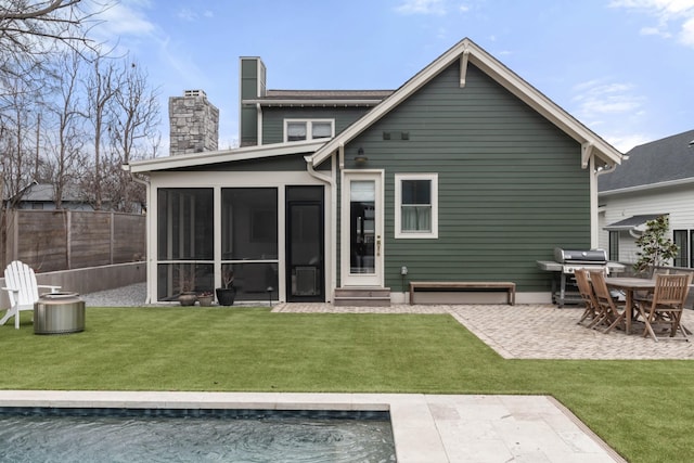 rear view of property with a sunroom, a yard, and a patio area