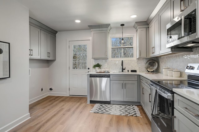 kitchen featuring appliances with stainless steel finishes, pendant lighting, and gray cabinetry