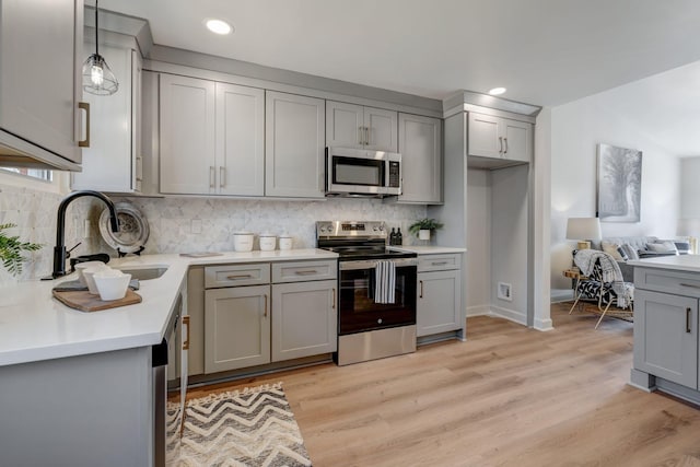 kitchen featuring sink, gray cabinetry, hanging light fixtures, stainless steel appliances, and decorative backsplash