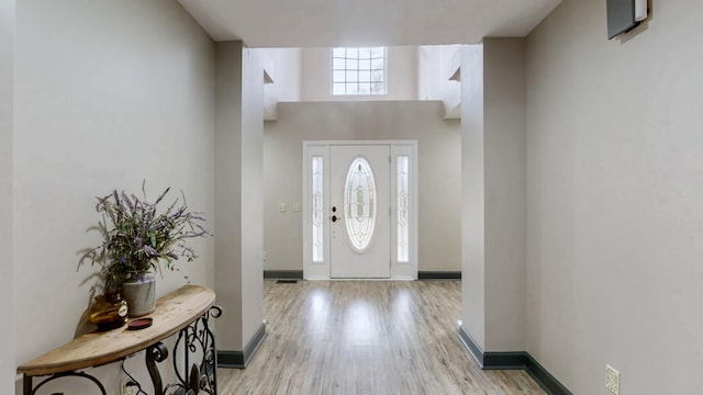 foyer with a towering ceiling and light hardwood / wood-style flooring