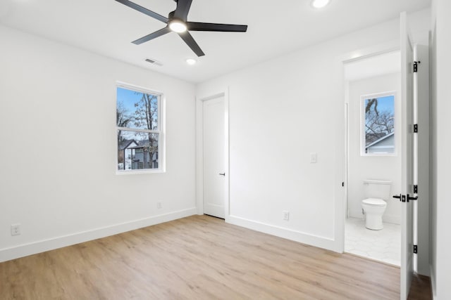 unfurnished bedroom featuring ceiling fan, ensuite bathroom, and light hardwood / wood-style floors