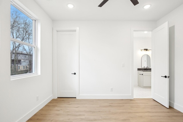 unfurnished bedroom featuring ceiling fan, ensuite bath, sink, and light hardwood / wood-style floors