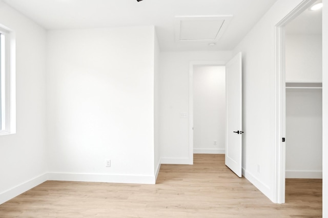 interior space featuring multiple windows, a walk in closet, a closet, and light wood-type flooring