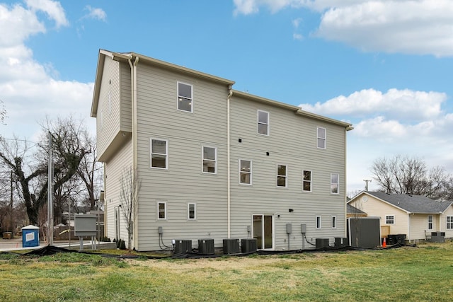 back of property with central AC and a yard