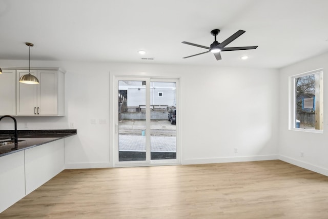 unfurnished living room featuring ceiling fan, light hardwood / wood-style floors, and sink