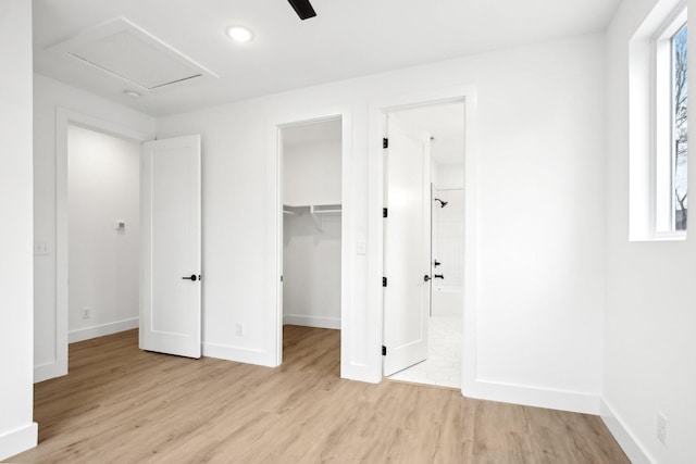 unfurnished bedroom with multiple windows, a spacious closet, light hardwood / wood-style flooring, and a closet