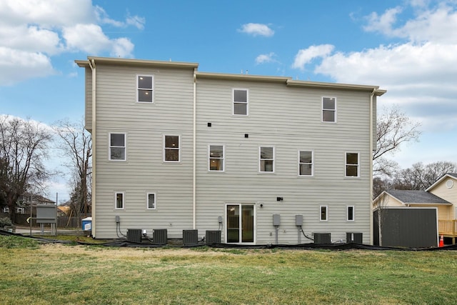 rear view of property with a lawn and central air condition unit