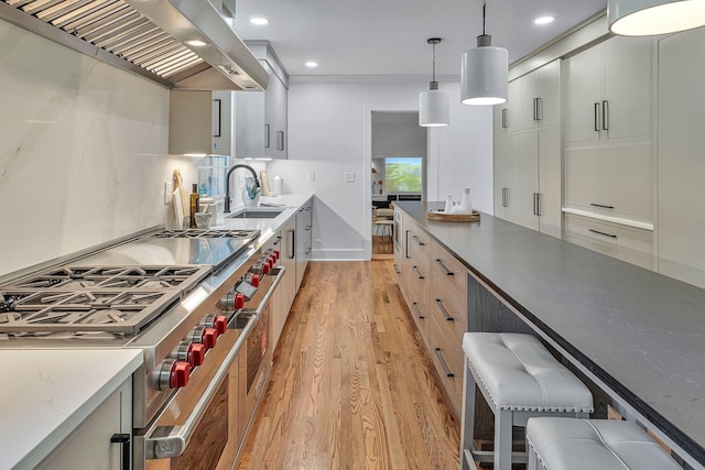 kitchen with ventilation hood, white cabinetry, range with two ovens, and decorative light fixtures