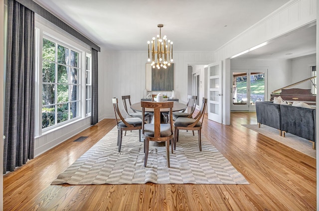 dining space with crown molding, a chandelier, and light hardwood / wood-style floors