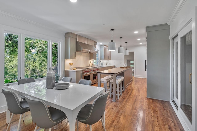 dining room with crown molding, light hardwood / wood-style floors, and sink