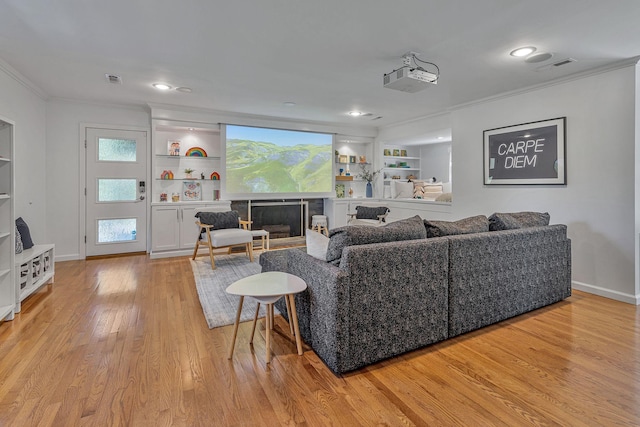 living room featuring built in shelves, light hardwood / wood-style flooring, and ornamental molding