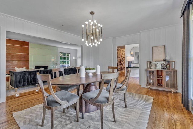 dining area with a notable chandelier, light hardwood / wood-style flooring, and ornamental molding