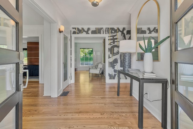 hallway with ornamental molding and light hardwood / wood-style floors