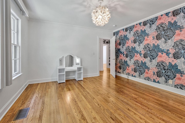 spare room with ornamental molding, a chandelier, and light hardwood / wood-style flooring