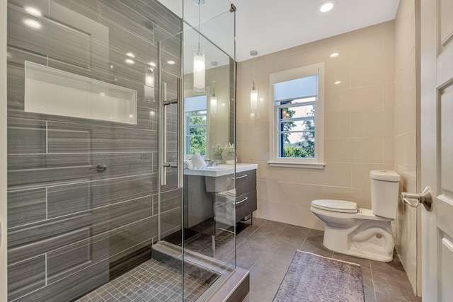 bathroom featuring walk in shower, tile patterned floors, toilet, tile walls, and vanity