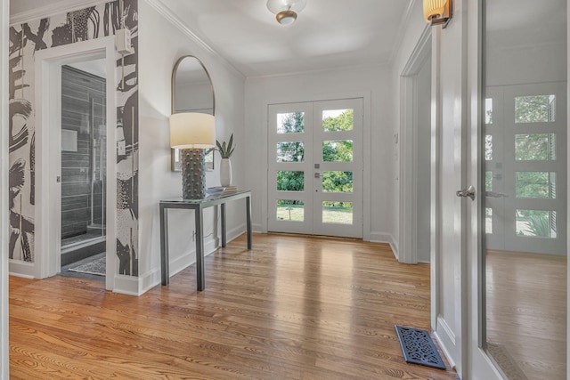 foyer with ornamental molding, wood-type flooring, and french doors