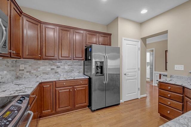 kitchen with light stone counters, decorative backsplash, light hardwood / wood-style floors, and appliances with stainless steel finishes