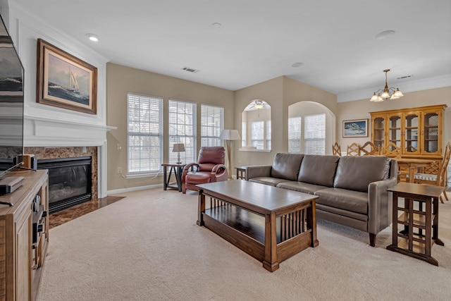 carpeted living room with a premium fireplace, a notable chandelier, and crown molding