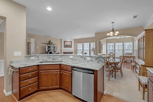 kitchen with light stone counters, sink, stainless steel dishwasher, and kitchen peninsula