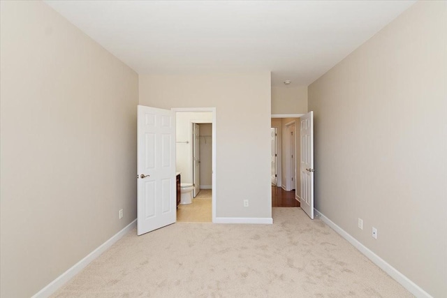 unfurnished bedroom featuring light carpet and a walk in closet