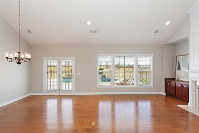 unfurnished living room with vaulted ceiling, wood-type flooring, and a chandelier