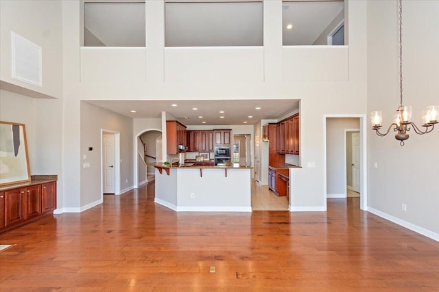 unfurnished living room featuring a notable chandelier, light hardwood / wood-style flooring, and a high ceiling