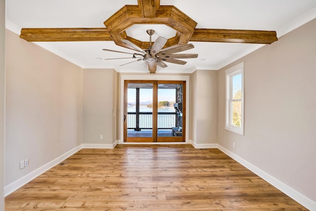 empty room featuring a healthy amount of sunlight, beam ceiling, and light hardwood / wood-style floors