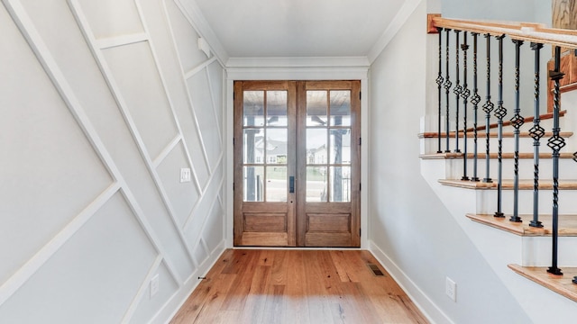 doorway featuring hardwood / wood-style floors, ornamental molding, and french doors