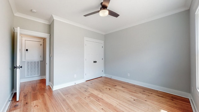 unfurnished bedroom featuring ornamental molding, a closet, ceiling fan, and light wood-type flooring