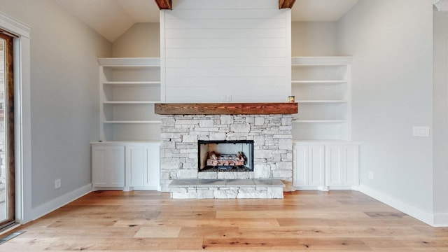 unfurnished living room with lofted ceiling, built in features, a fireplace, and light hardwood / wood-style flooring