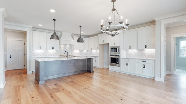 kitchen with stainless steel appliances, decorative light fixtures, custom range hood, and white cabinets