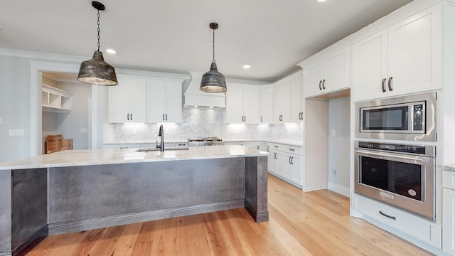 kitchen with appliances with stainless steel finishes, sink, hanging light fixtures, and white cabinets