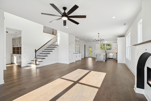 unfurnished living room with dark wood-type flooring and ceiling fan with notable chandelier