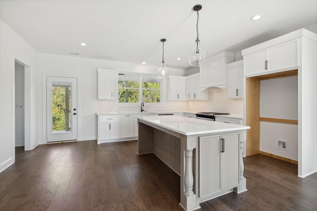 kitchen featuring premium range hood, stainless steel stove, a center island, and white cabinets