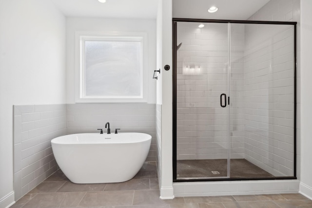 bathroom with tile patterned flooring, plus walk in shower, and tile walls