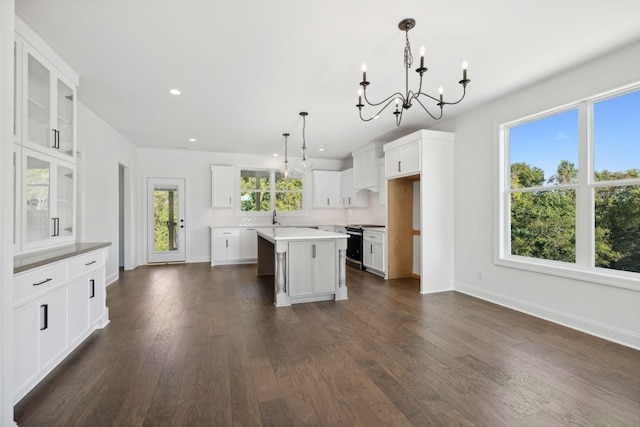 kitchen with pendant lighting, white cabinetry, an inviting chandelier, stainless steel range oven, and a kitchen island