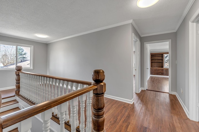 hallway with hardwood / wood-style floors, ornamental molding, and a textured ceiling