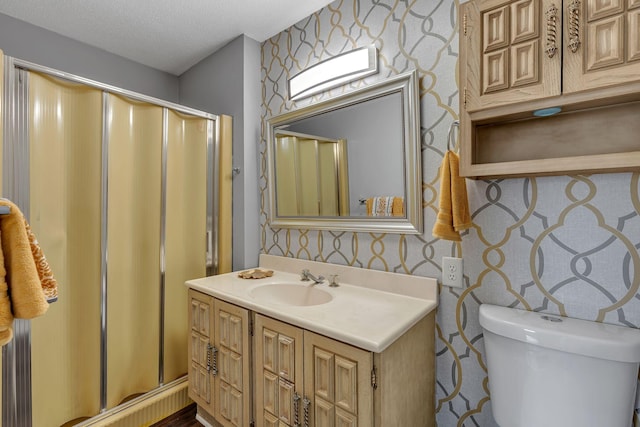 bathroom featuring vanity, a shower with door, toilet, and a textured ceiling